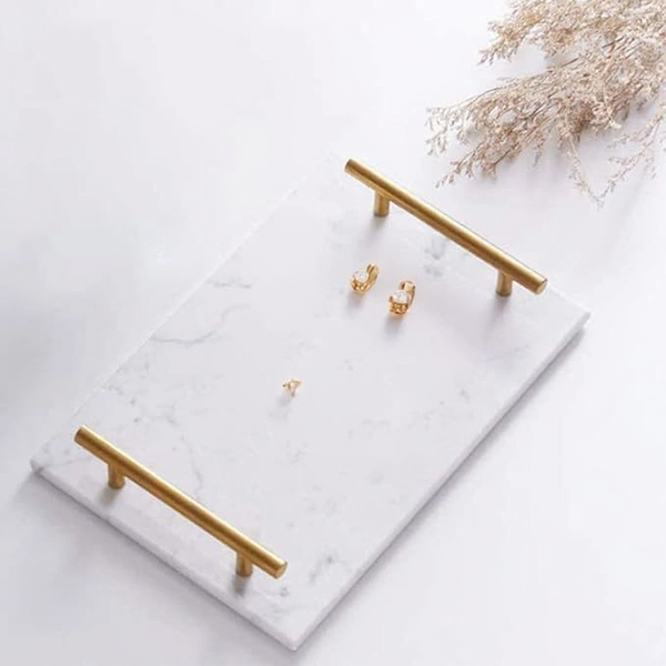 Gold earrings on a marble stand with a light background